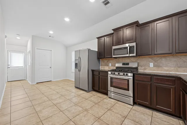 a kitchen with stainless steel appliances granite countertop a refrigerator and a stove top oven