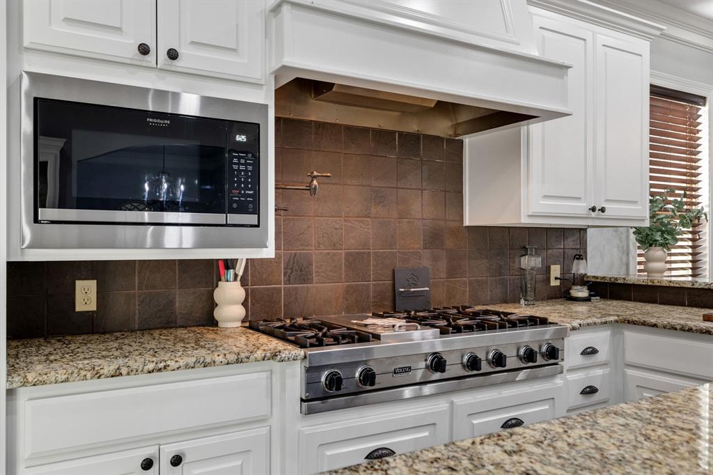 689 Jim Cannon Road Van Alstyne, TX 75495 - Photo 11 of 35 Kitchen featuring white cabinetry, light stone counters, stainless steel appliances, and decorative backsplash
