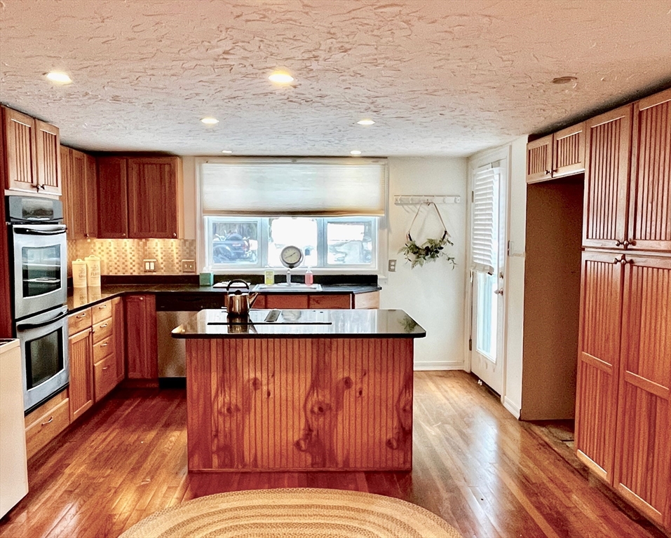 214-216 River Road East Berlin, MA 01503 - Photo 3 of 16 a kitchen with stainless steel appliances granite countertop a refrigerator a sink dishwasher a stove and white countertops with wooden floor