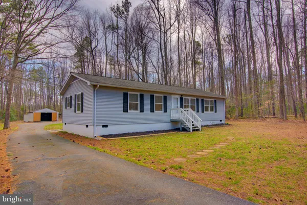 a front view of house with yard and trees in the background