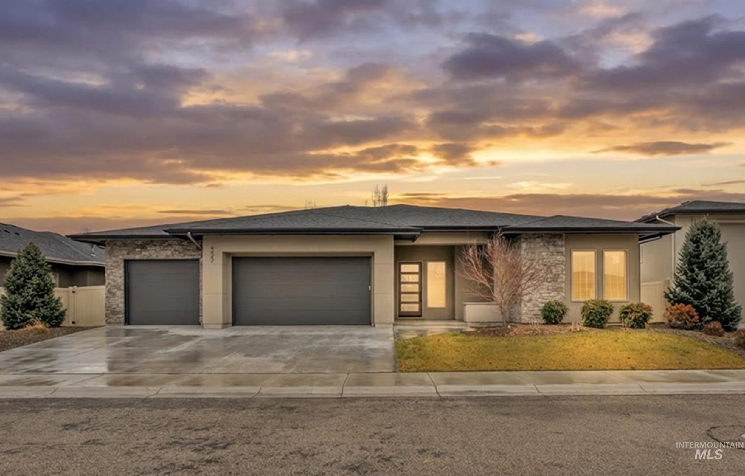 Prairie-style house featuring an attached garage, driveway, stucco siding, and stone siding