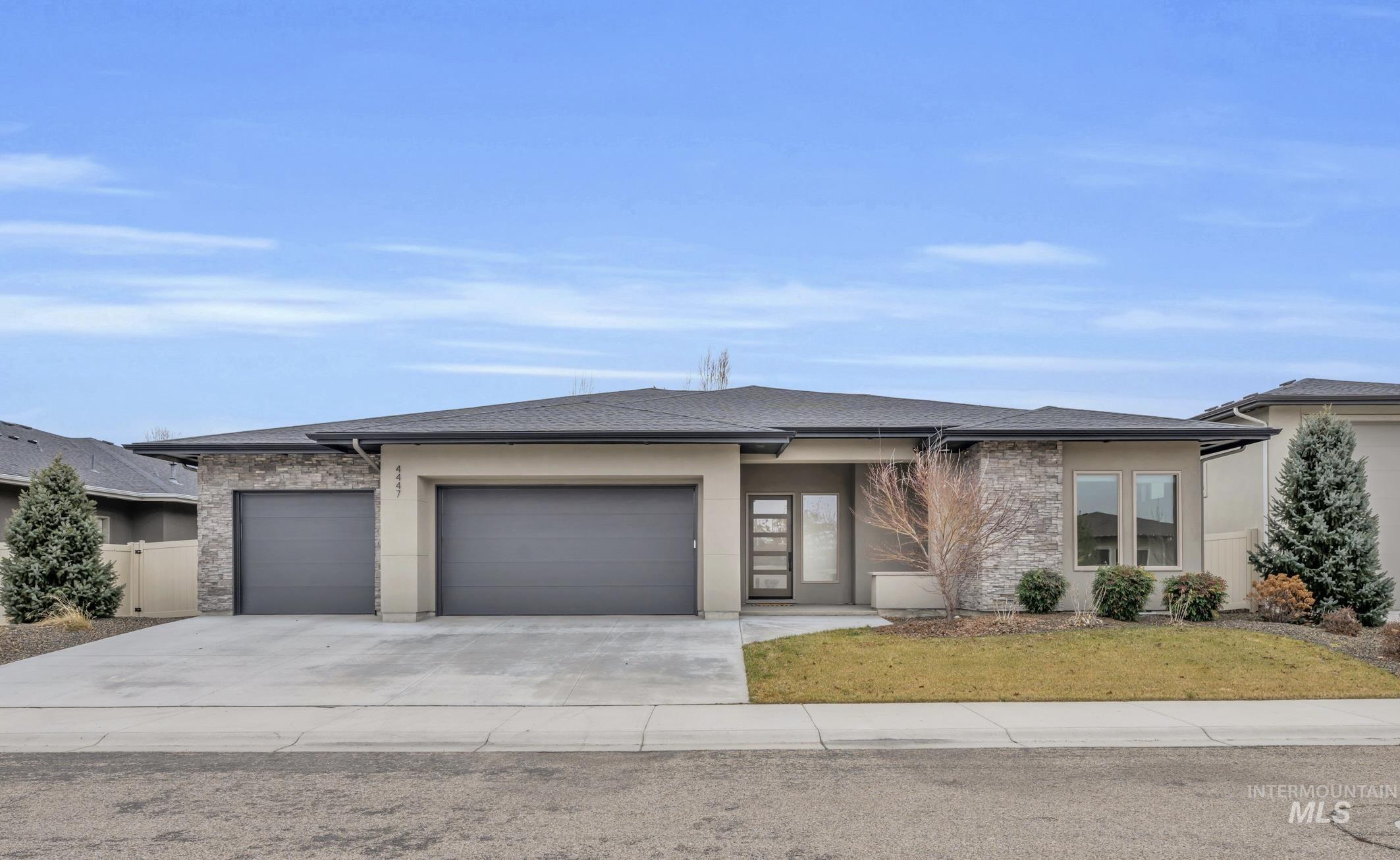 4447 East Copper Point Drive Meridian, ID 83642 - Photo 2 of 42 Prairie-style house featuring stone siding, a garage, driveway, and stucco siding
