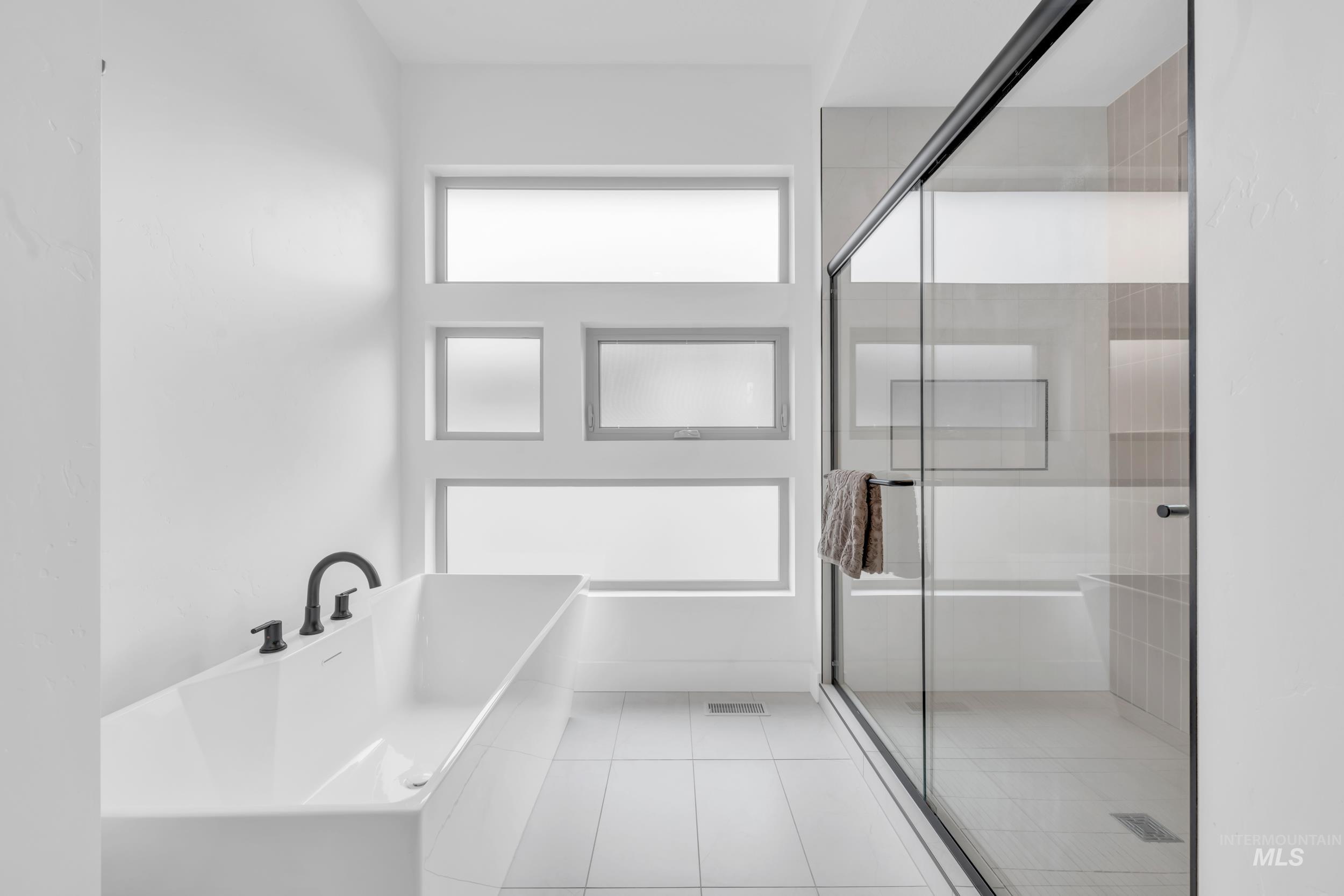 4447 East Copper Point Drive Meridian, ID 83642 - Photo 23 of 42 Full bathroom with a soaking tub, a shower stall, and light tile patterned floors