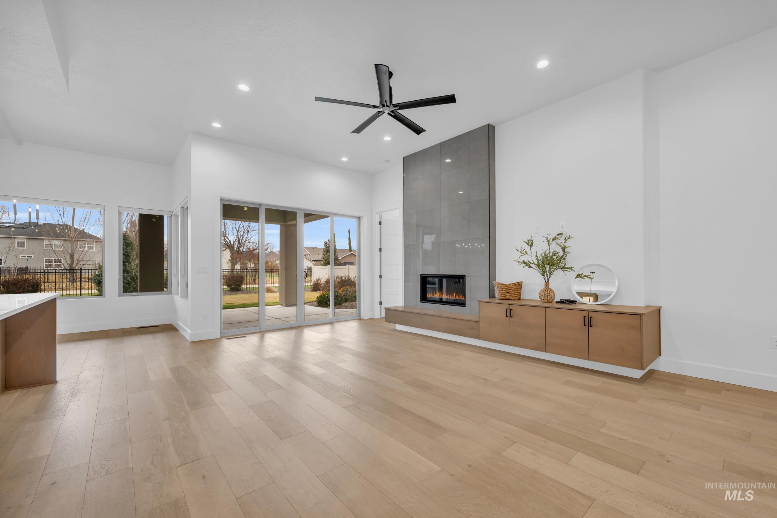 4447 East Copper Point Drive Meridian, ID 83642 - Photo 9 of 42 Unfurnished living room featuring a fireplace, light wood-style floors, recessed lighting, and a ceiling fan