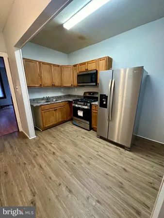 a kitchen with stainless steel appliances granite countertop a refrigerator a stove and a wooden floors