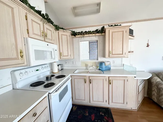 a kitchen with granite countertop a refrigerator a stove a sink dishwasher and white cabinets with wooden floor