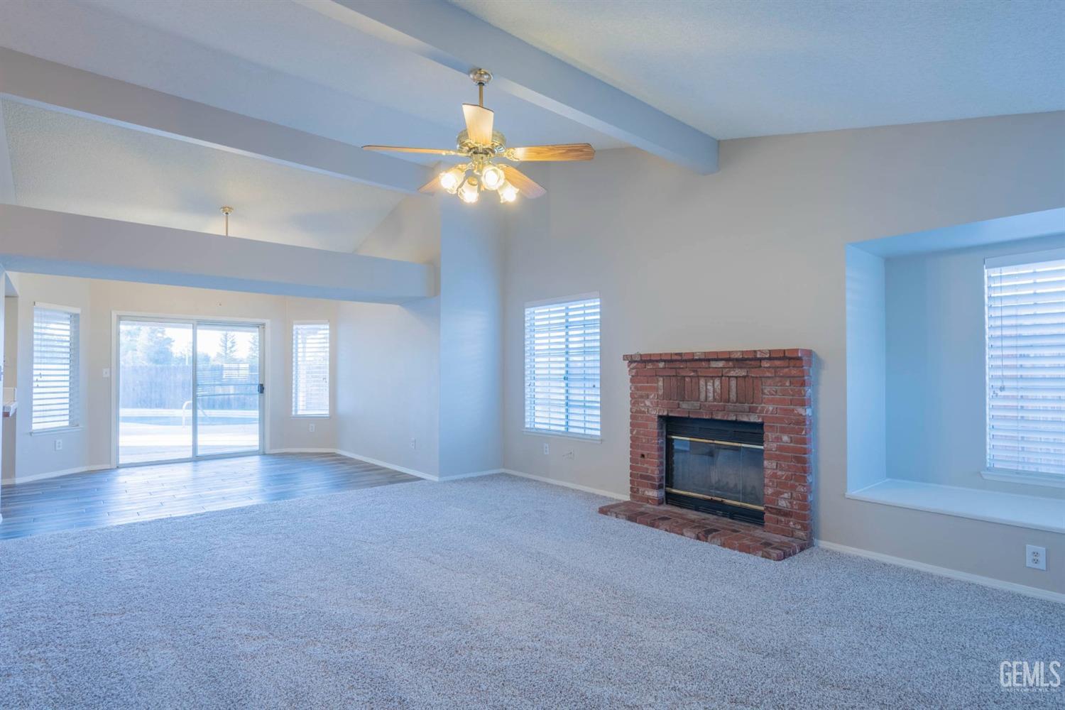 Undisclosed Address Bakersfield, CA 93314 - Photo 6 of 31 an empty room with windows fireplace and fan