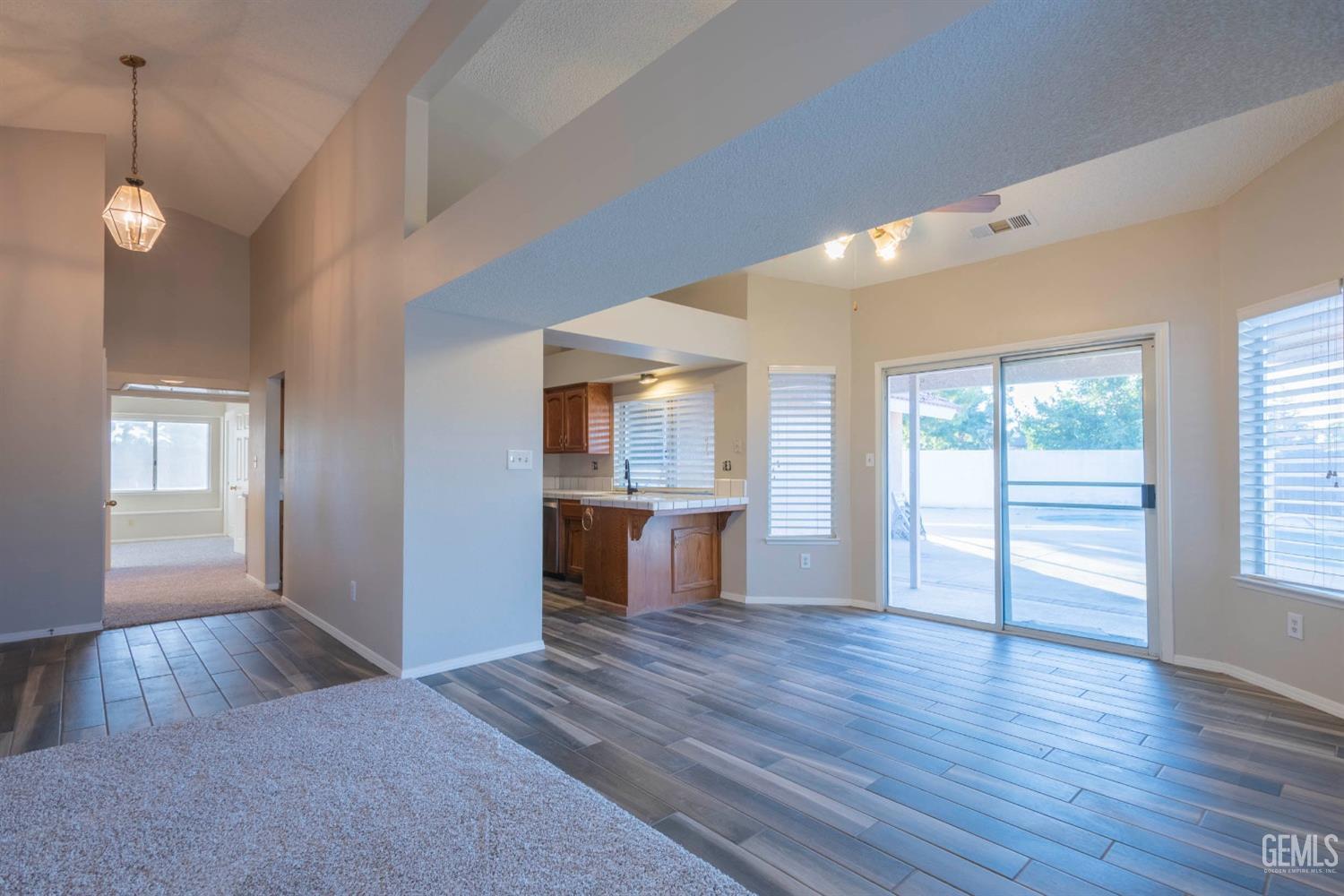 Undisclosed Address Bakersfield, CA 93314 - Photo 8 of 31 a view of a kitchen and an empty room with wooden floor and a kitchen