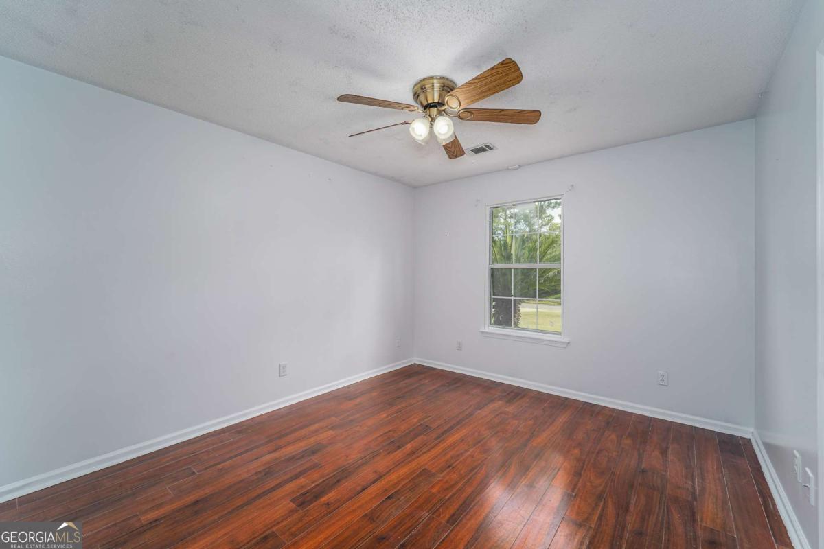 301 Ridge Lane Douglas, GA 31533 - Photo 22 of 26 a view of empty room with wooden floor and fan