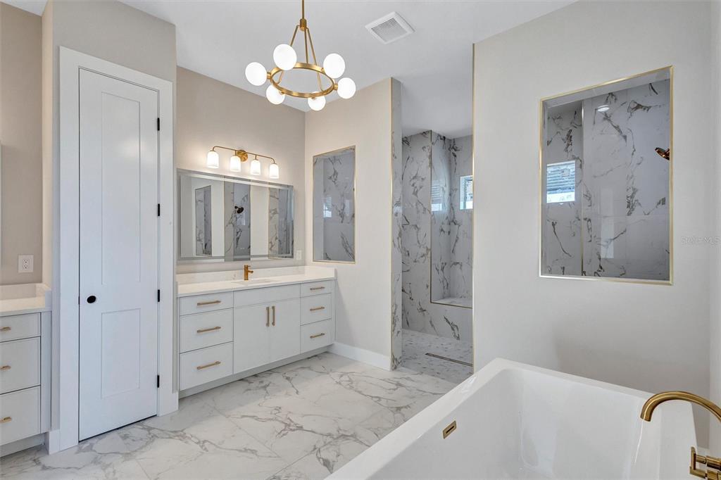 1613 148th Terrace East Parrish, FL 34219 - Photo 41 of 81 a spacious bathroom with a granite countertop sink a mirror a shower and a bathtub
