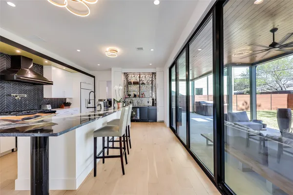 a kitchen with stainless steel appliances granite countertop a stove a refrigerator a sink and a dining table with wooden floor