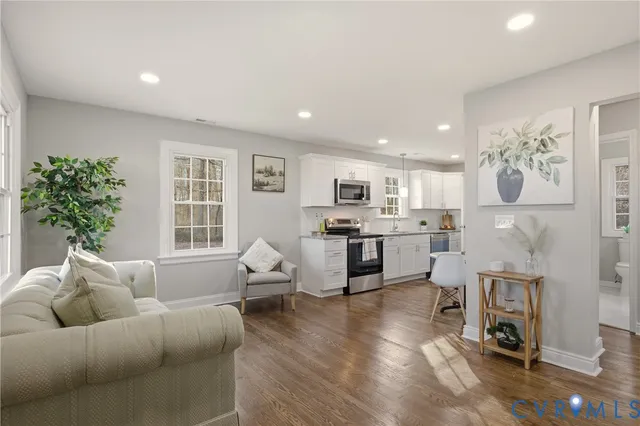 a living room with furniture and kitchen view with wooden floor