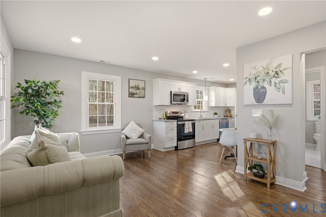 a living room with furniture and kitchen view with wooden floor