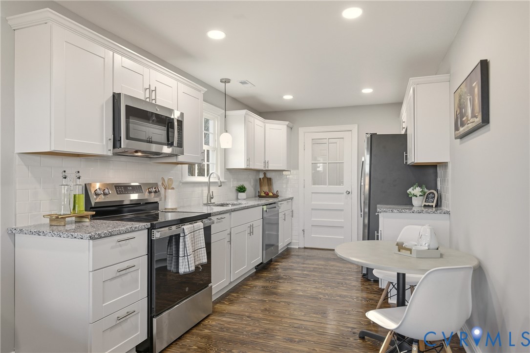 6280 Monahan Road Henrico, VA 23231 - Photo 6 of 42 a large kitchen with stainless steel appliances granite countertop a stove top oven a sink dishwasher and white cabinets with wooden floor