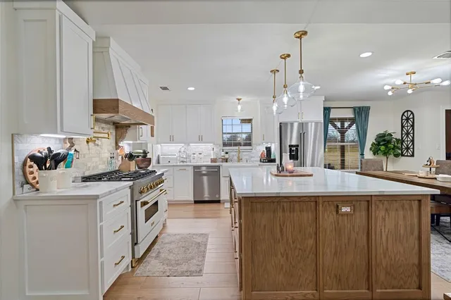 a kitchen with kitchen island granite countertop a sink cabinets and stainless steel appliances