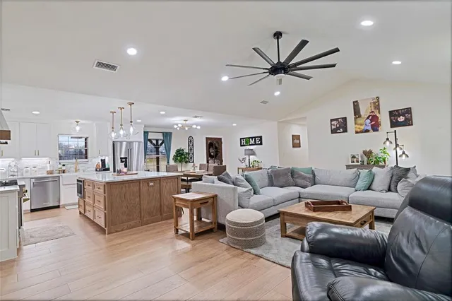 a living room with furniture kitchen view and a chandelier