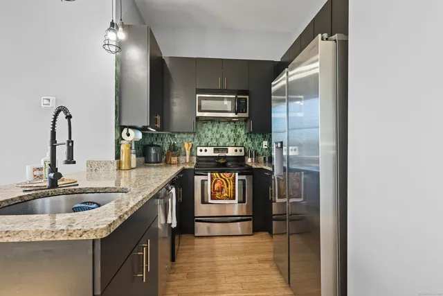 a kitchen with stainless steel appliances granite countertop a sink and a refrigerator