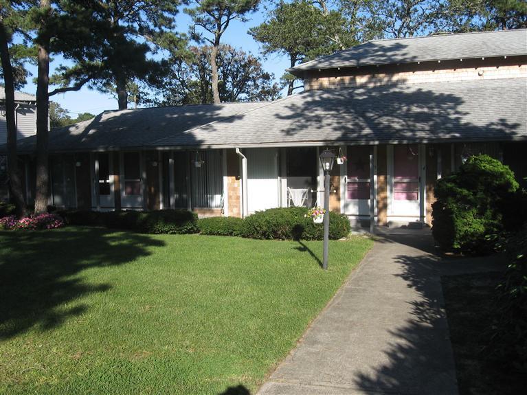 126 Lower County Road, Unit 6 Dennis Port, MA 02639 - Photo 10 of 12 a view of a white house with a yard and potted plants