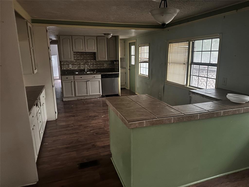1832 Smokehouse Road Granbury, TX 76049 - Photo 13 of 23 Kitchen featuring kitchen peninsula, stainless steel dishwasher, sink, and backsplash