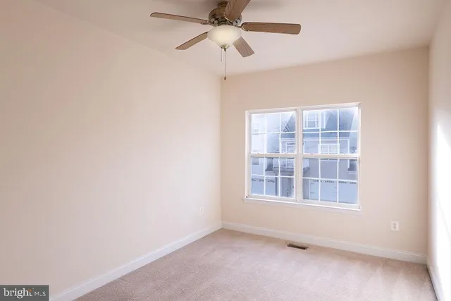 an empty room with a window and a ceiling fan