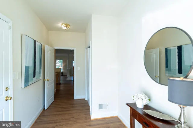a view of a hallway with wooden floor and a bathroom