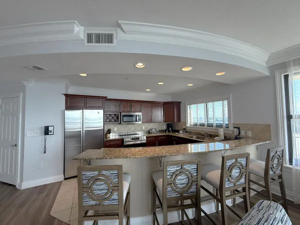 a kitchen with stainless steel appliances granite countertop a table chairs refrigerator and cabinets