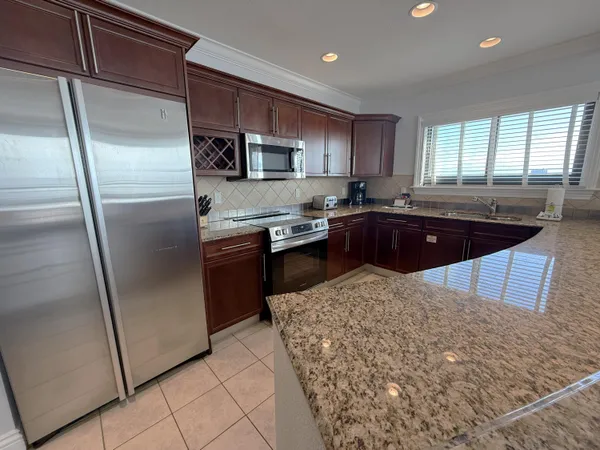 a kitchen with stainless steel appliances granite countertop a refrigerator a sink a stove a microwave and island