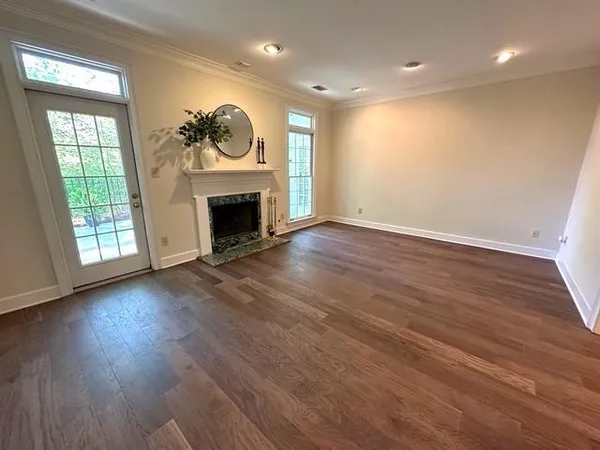 an empty room with wooden floor fireplace and windows
