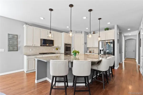 a kitchen with stainless steel appliances kitchen island granite countertop a dining table chairs and a refrigerator a sink