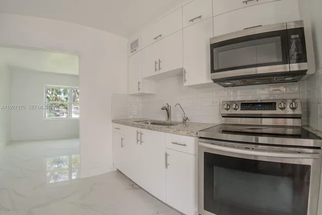 a kitchen with stainless steel appliances granite countertop white cabinets and stove top oven