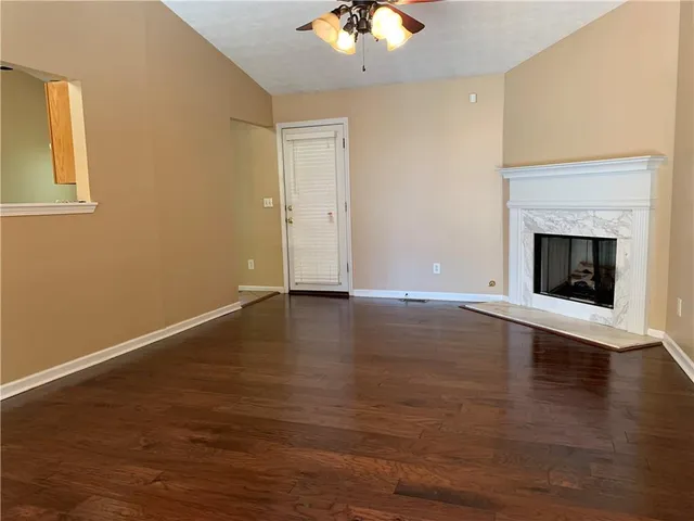 a view of an empty room with wooden floor and a fireplace