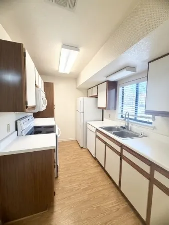 a large kitchen with a sink and dishwasher a stove top oven with wooden floor