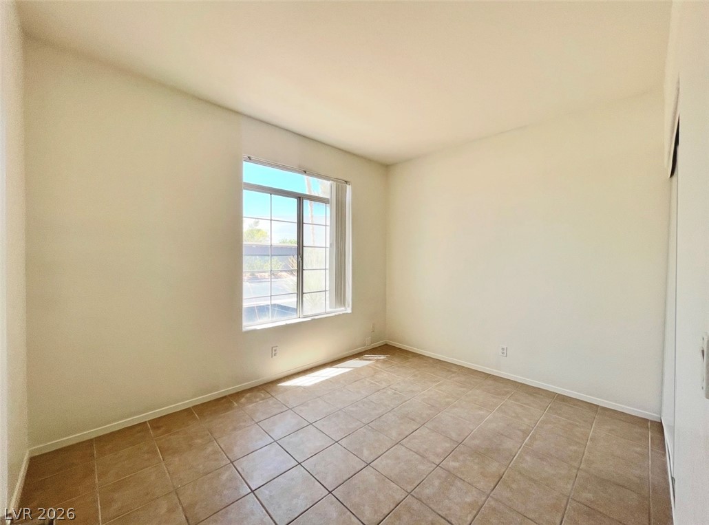 2201 Ramsgate Drive, Unit 915 Henderson, NV 89074 - Photo 33 of 36 A well-lit bedroom with ample space, featuring durable tiled flooring and a clear window offering views to the outdoors.