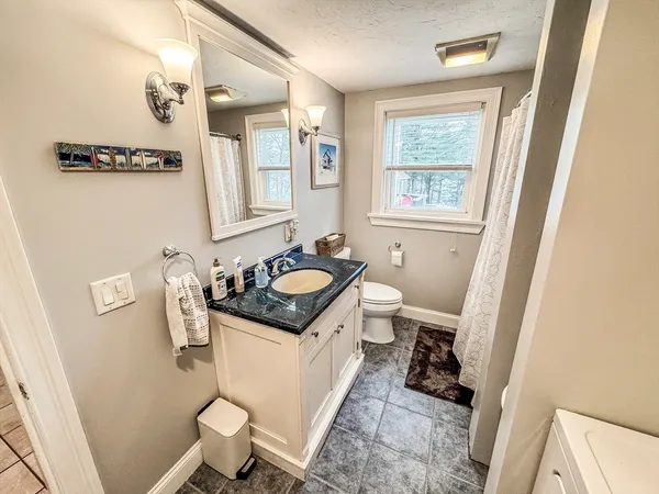 a bathroom with a sink a toilet a mirror and a window