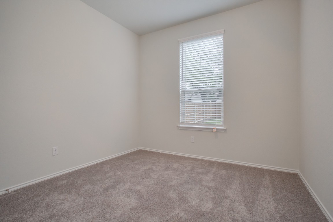 148 Spotted Rail Ridge Leander, TX 78641 - Photo 20 of 31 A well-lit, neutral-toned room features soft carpet flooring and a single window with blinds.