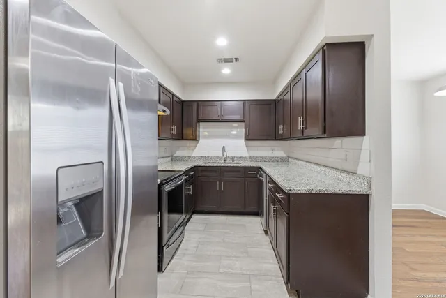 a kitchen with stainless steel appliances granite countertop a stove a refrigerator and a sink