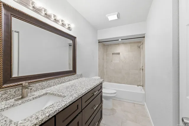a bathroom with a granite countertop sink a mirror and shower
