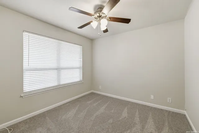 an empty room with a window and a fan