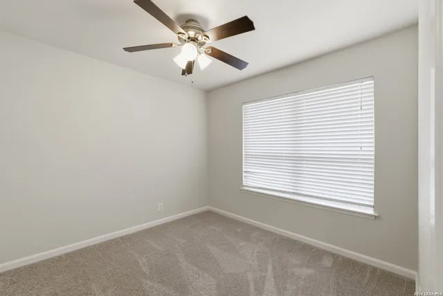 an empty room with a window and a fan
