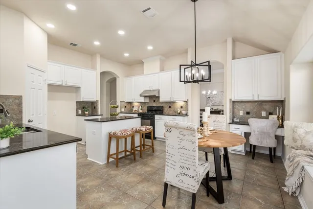 a kitchen with stainless steel appliances kitchen island granite countertop a sink a stove a dining table and chairs