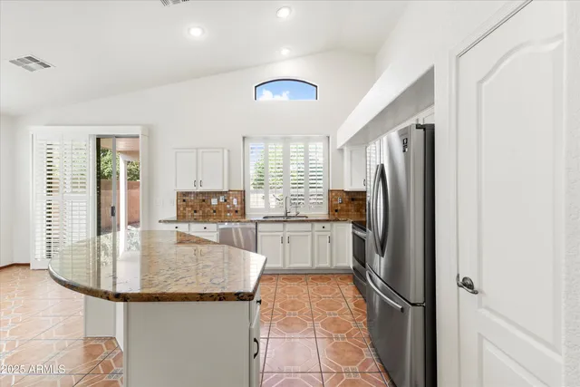 a kitchen with stainless steel appliances granite countertop a sink a stove and a refrigerator