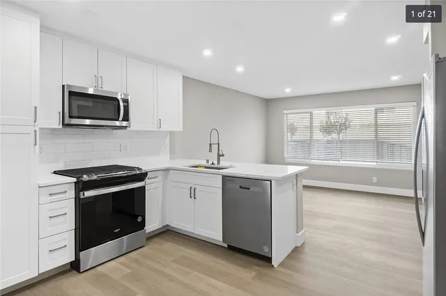 a kitchen with stainless steel appliances granite countertop a stove a sink and a microwave