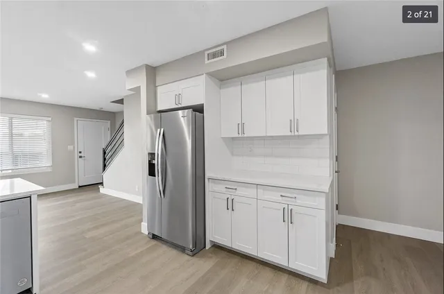 a kitchen with white cabinets and refrigerator