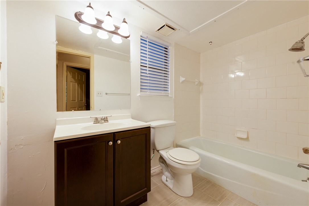 706 West 22nd Street, Unit 202 Austin, TX 78705 - Photo 13 of 24 a bathroom with a toilet a sink a mirror and a bathtub