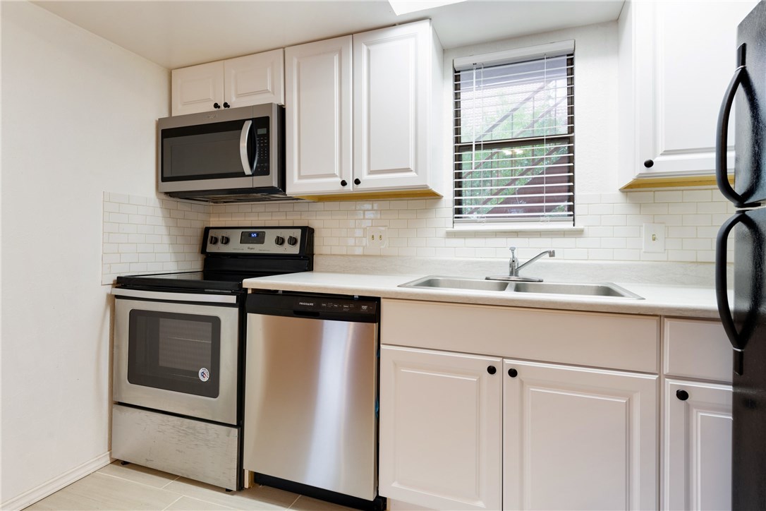 706 West 22nd Street, Unit 202 Austin, TX 78705 - Photo 15 of 24 a kitchen with stainless steel appliances granite countertop white cabinets a sink and a microwave