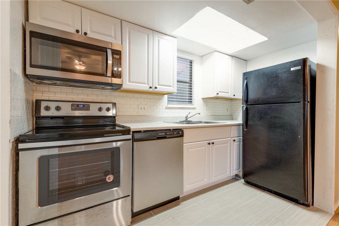 706 West 22nd Street, Unit 202 Austin, TX 78705 - Photo 16 of 24 a kitchen with granite countertop white cabinets stainless steel appliances and a counter space