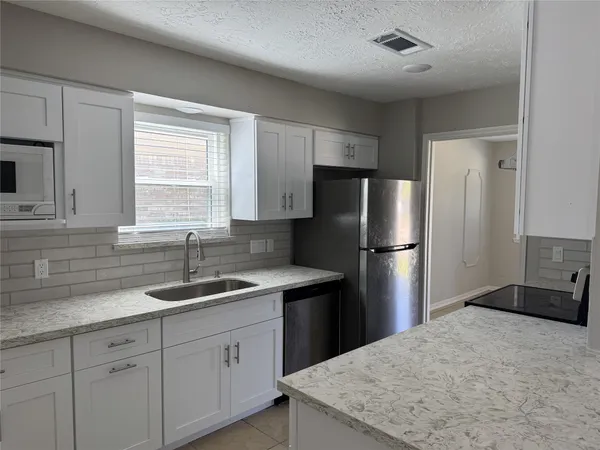 a kitchen with kitchen island granite countertop white cabinets refrigerator and window
