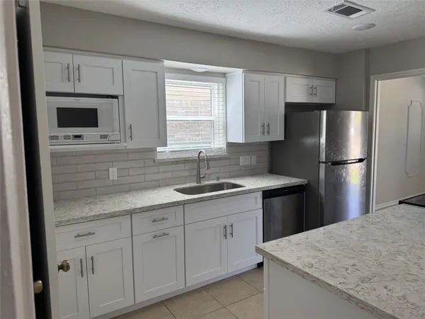 a kitchen with kitchen island granite countertop a sink stove and refrigerator