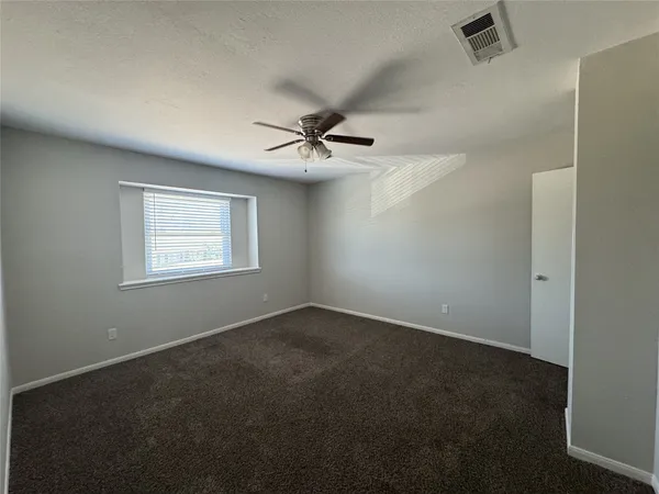 an empty room with a window and a ceiling fan