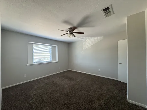 an empty room with a ceiling fan and windows